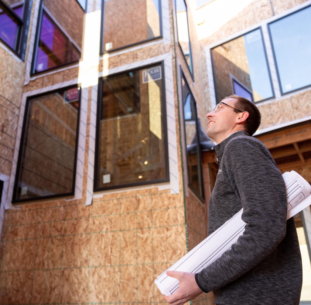 man holding set of plans looking up new construction